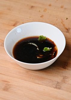 a white bowl filled with black sauce on top of a wooden table next to a knife