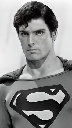 black and white photograph of man in superman costume looking at the camera with serious look on his face