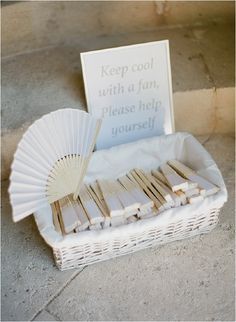 a white basket filled with wooden forks and paper fan next to a sign that says keep cool