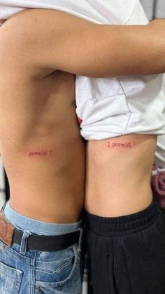 two people with tattoos on their stomachs, one is holding the other's back