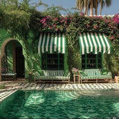 an outdoor swimming pool with green and white striped awnings next to lounge chairs