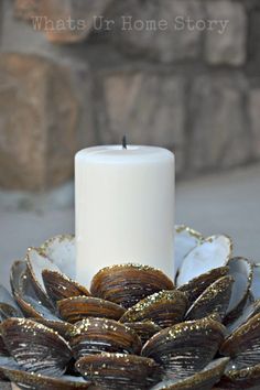 a candle sits in a bowl filled with seashells