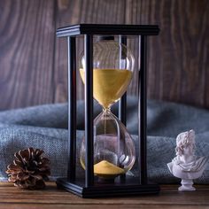 an hourglass sitting on top of a table next to a pine cone and figurine