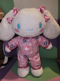 a white stuffed animal with pink and blue designs on it's face sitting in a chair