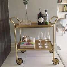 a gold bar cart with glasses and bottles on it