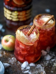 two cocktails with cinnamon garnish and apples in the background