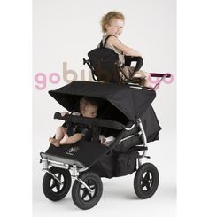 two children sit in strollers with black covers