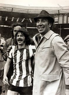 two men standing next to each other in front of an audience at a soccer game