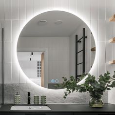 a bathroom with a large round mirror on the wall and plants in front of it