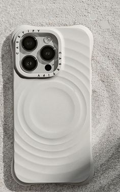 an iphone case sitting on top of sand next to a white object with black buttons