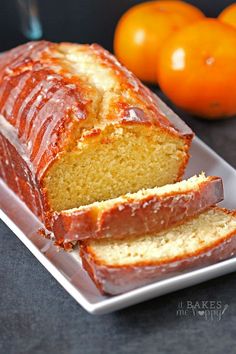 a loaf of orange pound cake sitting on top of a white plate next to some oranges