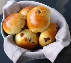 a bowl filled with bread rolls on top of a table