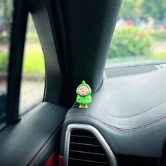 a green toy sitting on the dashboard of a car