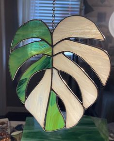 a green and white leaf hanging from a chain