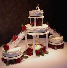 three tiered wedding cake with red roses on the table