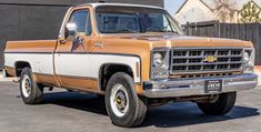 an orange and white pickup truck parked in a parking lot next to a black building