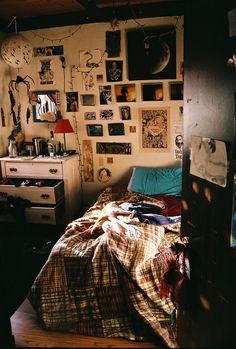 a bed sitting in a bedroom next to a wall covered in pictures and posters on it