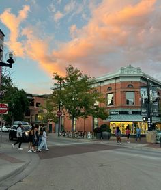 people are walking on the street in front of a building at sunset or sunrise time