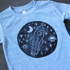 a blue t - shirt with an image of a rocket ship on it