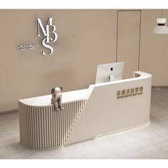 a small teddy bear sitting on top of a white reception desk in front of a logo