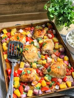 a pan filled with chicken and vegetables next to a bowl of rice