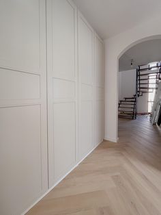 an empty room with white walls and wood floors, along with stairs leading to the second floor