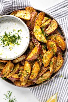 baked mediterranean potato wedges in a bowl with ranch dip and herbs on the side