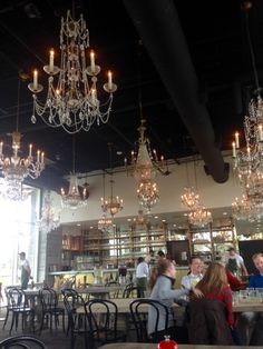 people sitting at tables with chandeliers hanging from the ceiling