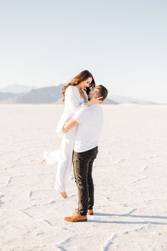 a man carrying a woman on his back in the middle of an open desert area