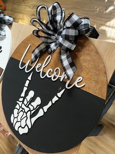 a welcome sign on top of a wooden table with black and white ribbon tied around it