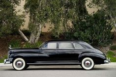 an old black car is parked on the street