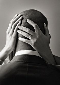 two hands on the back of a man's head as he covers his face