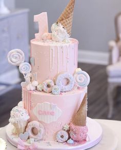 a pink birthday cake with ice cream and donuts on the top is decorated in pastel colors