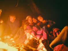 a group of people sitting around a campfire