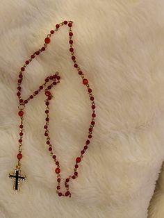 This is made using gold wire and red round beads. Every 10th stone is a red faceted bread. The cross is finished in 30 crystals surrounding a black shiny painted t shaped metal pendant. This can be used for any occasion Red Spiritual Jewelry With Black Beads, Spiritual Red Jewelry With Black Beads, Handmade Red Cross Pendant Jewelry, Handmade Red Crucifix Jewelry, Red Spiritual Cross Pendant Jewelry, Red Spiritual Jewelry With Gold Beads, Red Crucifix Cross Necklace Gift, Spiritual Red Jewelry With Gold Beads, Red Crucifix Cross Necklace For Gift