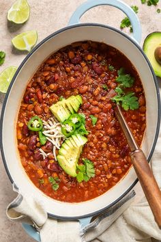 a bowl filled with beans, avocado and cilantro on top of a table