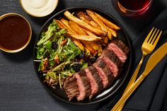 steak, fries and salad on a black plate