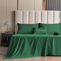 a bed covered in green sheets and pillows