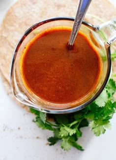 a glass jar filled with sauce and garnished with cilantro