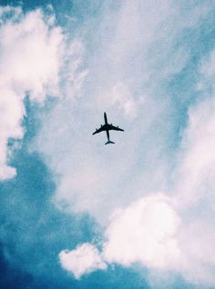 an airplane is flying in the sky on a cloudy day with blue and white clouds