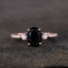 a black and white diamond ring sitting on top of a gray stone surface with diamonds around it