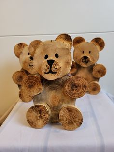 three wooden teddy bears sitting on top of a bed