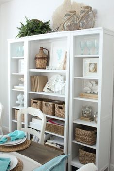 a white bookcase filled with lots of books and wicker baskets on top of it