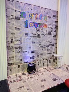 a room with newspaper covering the walls and a red chair on the floor in front of it