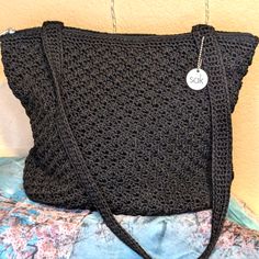 a black crocheted purse with a white tag hanging from it's side