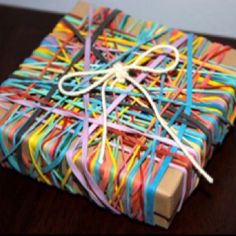 a wrapped gift box is covered in multicolored paper streamers and twine