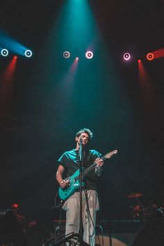 a man that is standing up on a stage with a guitar in front of him