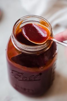 a person is holding a spoon full of jam