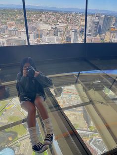 a woman taking a photo from the top of a glass floored building with her cell phone