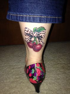 a woman's foot with tattoos on it and cherries painted on the side